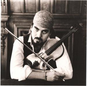 A dark eyed man with goatee and a head-scarf holds his Luigi Rovati violin and bow