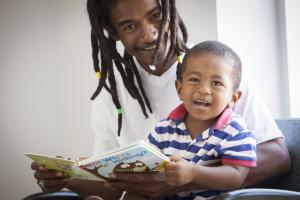 A father reads to his child during a well visit. The book was donated through the Reach Out and Read program.