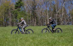 two bike riders on electric bikes ride along a trail