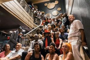 An intergenerational group of dozens of Black folks gather proudly for a community photo on a staircase during the 2022 International Lindy Hop Championships.