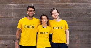 Left to right: Larry Kotch (CCO), Andrea Jagodic (CEO), Thomas Stringer (CFO) stand together with arms around eachother against a wooden wall