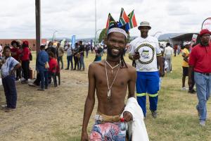 The image portrays a man in traditional clothing attending the 2023 TB Day event at Thlabane and engaging with the activities, highlighting the importance of TB awareness and prevention in all communities.