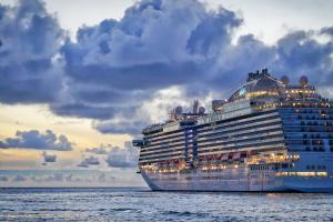 A cruise ship that Royal Holiday Vacation Club can provide to members sails on the ocean at dusk