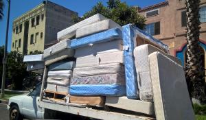 white pickup truck full of old dirty mattresses headed to landfill, aka "the dump"