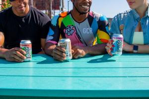 A photo of three people holding The Set Up cans in their hands