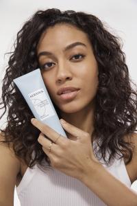 Model with curly hair holding KERASILK product curl balm