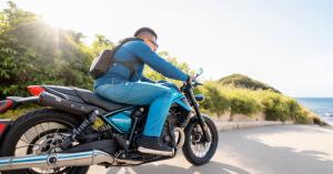 A person riding a motorcycle on a road near the ocean wearing Men's biker jeans from Jeans4you.shop's 2023 Summer Collection