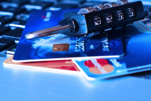 Three credit cards and a small combination lock lying on a keyboard.