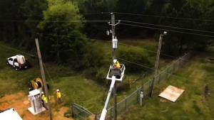 Photo of engineers attaching networking equipment to telephone poles