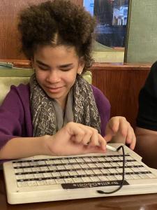 A Hispanic girl about 13 is examining the BrailleDoodle