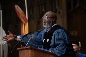 Man in theological robes preaching with one arm extended