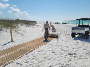 Park staff at Topsail Hill Preserve State Park unroll new mobility mat provided by the St. Joe Community Foundation.