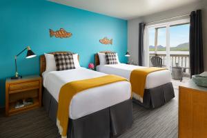 Picture of a typical guest room at The Ketch, in Ketchikan, Alaska. The new interior scheme by artist and designer Henry Chebaane, featuring teal blue, burnt orange, indigenous art, flannel cushions by Carhartt