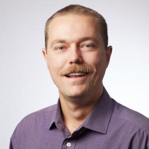 Tulley Kearney stands in front of a white background, he is wearing a purple shirt