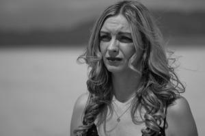 still black and white photo from the experimental short film, You Don't Deserve This. The photo shows the actress Shaun Rylee looking to her right while standing in the middle of the desert.