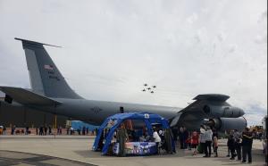 Captain Mama booth set up under the right wing of a KC-135R refueling tanker at Fairchild Air Force Base; the Air Force Thunderbirds are flying overhead