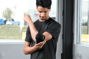 Tennis player stands with VibraCool EasyFit on his elbow to treat pain.