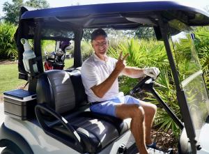 Golfer in Golf Cart Smiles as He Awaits Turn for Million Dollar Shot at EHAS INC's Charity Golf Event.