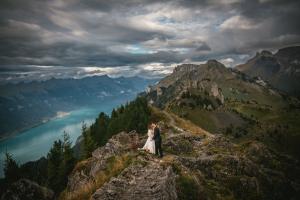 Couple standing on top of a mountain in Switzerland, echanging their vows at sunset with a lake in the background