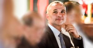 Man, Sebastien Abric, seated and gazing off frame smiling