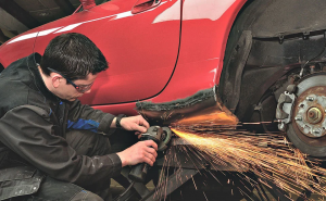 Technician talking grinder to vehicle panel