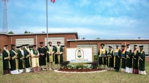 Picture of IQOU Theological College President, Faculty and Graduation Class of 2023 around an IQOU sign