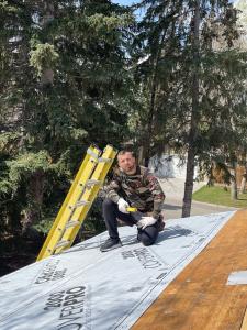 The owner of Calgary Roof Repair Ltd on a roof, Pashk Vukaj.