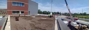 Panoramic view of the construction of the school includes cranes bringing up vegetated roofing components.