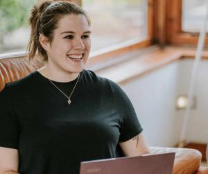 Elizabeth Goddard sits at her retreat with a laptop.
