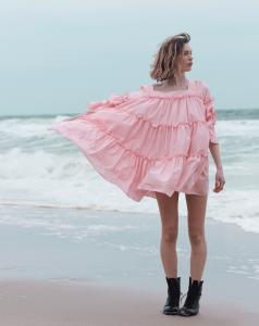 Model wearing NISH NICHE pink linen ruffled dress by the beach