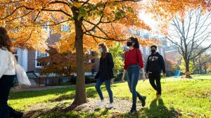 John Hopkins University students walking across campus beneath trees and sunshine.