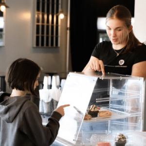 Intentional Foods staff helping a young girl pick out a treat from the display case