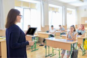 A teacher shown in a classroom full of students reviewing PHOTAVIA on a pad.