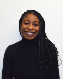 A photo of a Black woman wearing a black turtleneck in front of a white background.