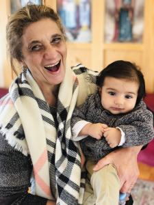 Image: Dr. Dalal Akoury, a loving mother and grandmother, cradles her grandson in her arms, radiating joy and warmth. The photo captures the special bond between them, symbolizing the nurturing connection shared through generations.