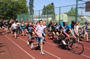Local youth run with the cyclists as they head to the next location in their 41-city tour of the country for 2023.