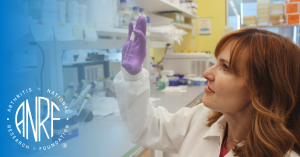 Scientist Heather Faust, Ph.D. examines a test tube in her lab, surrounded by equipment