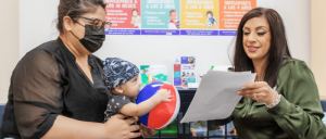 Mother holding young son as Variety team member sits at desk as they speak