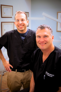 Dr. Canal and Dr. Calem standing together smiling in the office of Canal Calem Periodontics