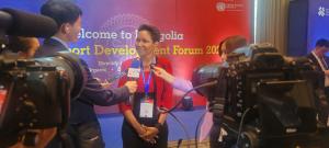 A woman with a microphone is interviewed by the media.