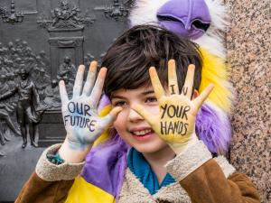 Child with message painted on his palms: Our Future, Your Hands