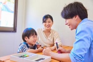 Young boy smiles and does crafts with parents at Nijigen no Mori