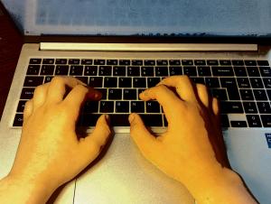 Image shows two hands on a laptop keyboard, most of the laptop screen is not visible