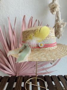 A woven style hat decorated with feathers, ribbons and other embellishments made during a hat bar party at dWELLing home decor and apparel