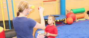 Boy working with ACE therapist on motor skills with ball