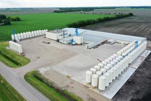 An aerial view of Northern Tier Seed location in Thompson, ND reveals a large building and grain silos nestled in between trees of a large area of fields.