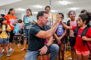 Man in blue shirt high fives a child wearing a backpack