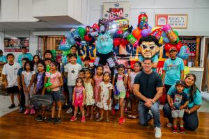 Man in blue shirt in a crowd of children with backpacks.