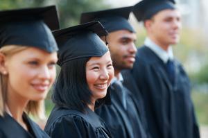 The graduates wearing their academic gowns happily pose for a group photo