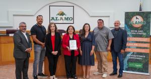 Tres mujeres y cuatro hombres, que son representantes de Schneider Electric y la Ciudad de Alamo, sonríen durante la ceremonia de presentación del Premio al Socio Innovador. La mujer en el centro sostiene la pequeña placa blanca y verde del premio.